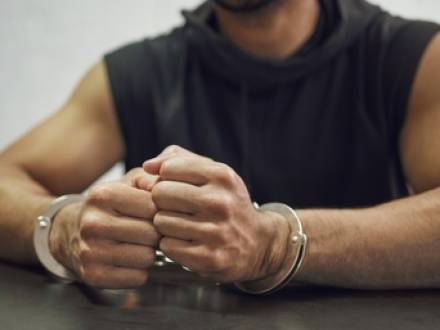 A close-up of a person's hands in handcuffs resting on a table
